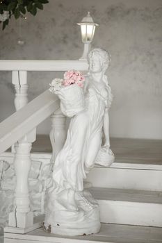 Sculpture of a girl with a basket of flowers standing by the stairs