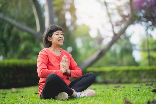 Senior asian woman practicing yoga lesson, breathing, meditating in garden. Working out, Well being, wellness concept