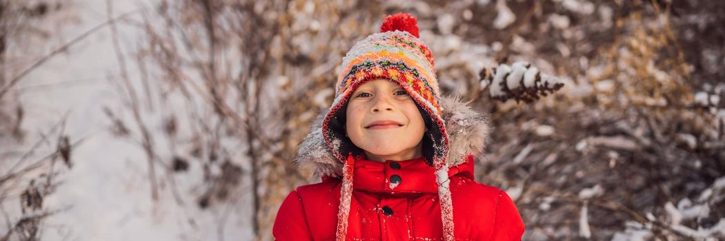 Boy in red fashion clothes playing outdoors. Active leisure with children in winter on cold days. Boy having fun with first snow. Happy little kid is playing in snow, good winter weather. BANNER, LONG FORMAT