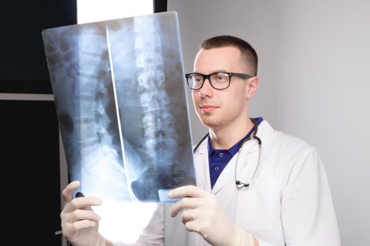 surgeon examines x-ray. spinal x-ray. health problems. nurse checking x-ray in hospital. An experienced male doctor interprets an x-ray. man looks