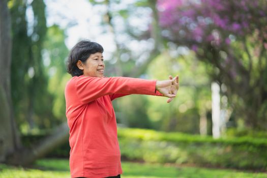 Senior asian woman body warming before exercising. Old woman stretching before jogging in garden, Sport athlete running concept.