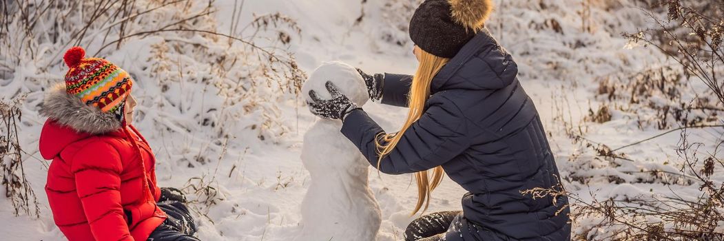 Happy family in warm clothing. Smiling mother and son making a snowman outdoor. The concept of winter activities. BANNER, LONG FORMAT