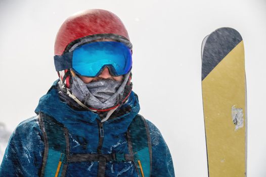 Closeup portrait of ski goggles of a man with reflection of snowy mountains. The mountain range is reflected in the ski mask. Portrait of a man in a ski resort against the backdrop of mountains and sky in a snow blizzard.