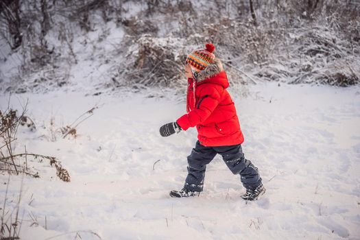 Cute boy in red winter clothes runs fun in the snow. Winter Fun Outdoor Concepts.