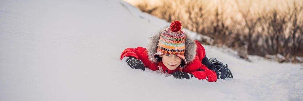 Boy in red fashion clothes playing outdoors. Active leisure with children in winter on cold days. Boy having fun with first snow. Happy little kid is playing in snow, good winter weather. BANNER, LONG FORMAT