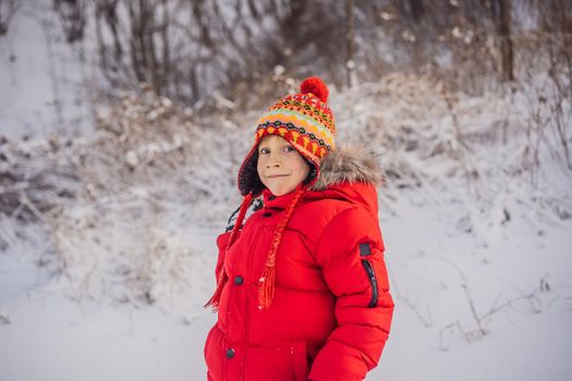 Boy in red fashion clothes playing outdoors. Active leisure with children in winter on cold days. Boy having fun with first snow. Happy little kid is playing in snow, good winter weather.