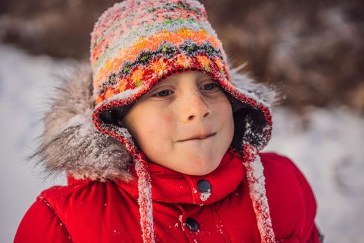 Boy in red fashion clothes playing outdoors. Active leisure with children in winter on cold days. Boy having fun with first snow. Happy little kid is playing in snow, good winter weather.