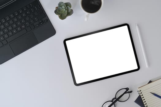 White office desk with digital tablet, laptop, glasses and notebook. Top view.