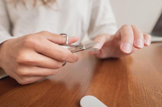 Close-up of hand of caucasian young woman doing manicure at home with nail supplies