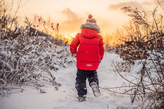 Cute boy in red winter clothes runs fun in the snow. Winter Fun Outdoor Concepts.