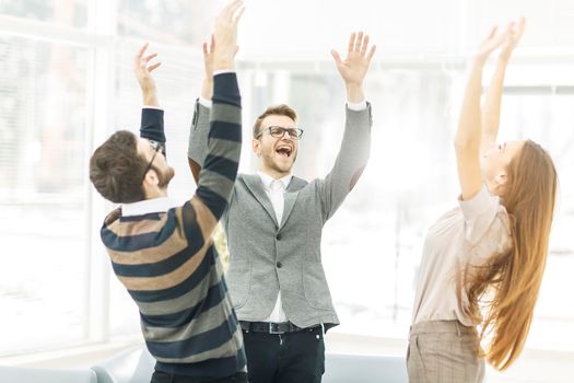 jubilant business team standing in a circle, hands up in rejoice success.the photo has a empty space for your text.