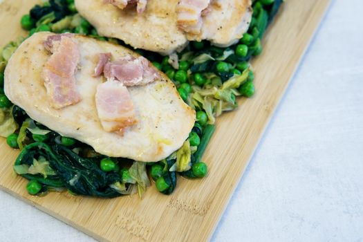 Chicken breast with bacon and vegetable salad on a wooden Board. Homemade food, cooking at home. Healthy food.