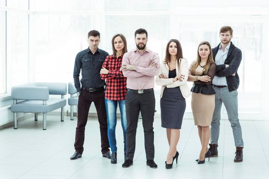 professional business team with arms crossed in front of him, standing on the background of the modern office