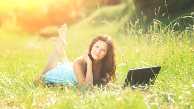 Beauty girl with laptop outdoors in a park on a sunny day