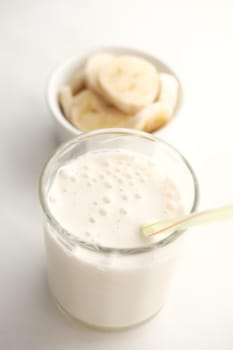 close up of slice of banana glass of milk on table .