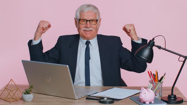 I am strong and independent. Senior office businessman showing biceps, looking confident, feeling power strength to fight for rights, energy to gain success win. Elderly man on pink studio background