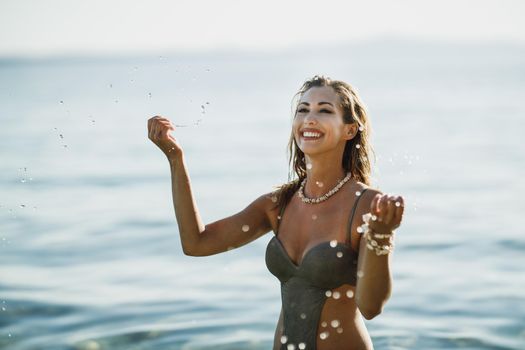 A beautiful smiling woman is having fun in the sea water and enjoys on vacation.