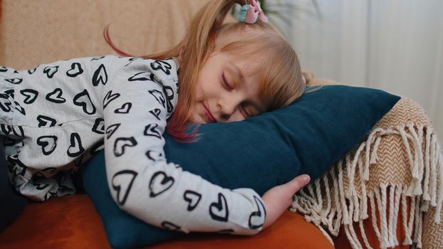 Portrait of little teen children girl sleeping, enjoying carefree peaceful weekend relaxation on couch at home alone. Small cute school toddler child kid resting, lying asleep, feeling lack of energy