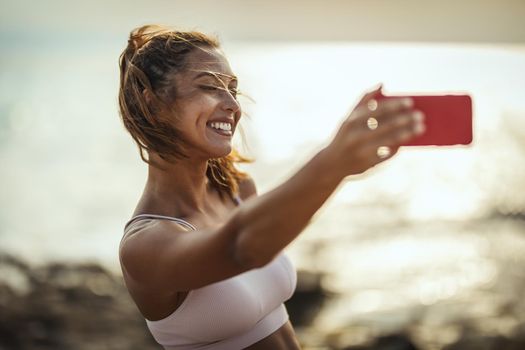 A beautiful young woman making selfie by smartphone, at the sea beach in summer sunny day.