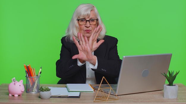 Stop. Senior businesswoman say No hold palm hand in Stop gesture, warning of finish, prohibited access, declining communication, body language, danger at office. Elderly woman on green chroma key