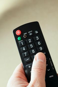 Hand with a remote in front of a green background