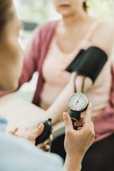 Close-up of a nurse checking the blood pressure to senior woman.