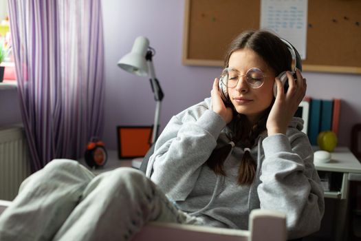 Listening to music on headphones. Young European girl. Teenage girl enthralled with new music. Closed eyes and hands on headphones.