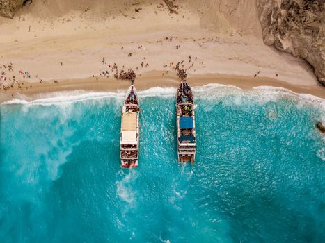 Aerial view from drone of amazing azure beach with rocky mountains and clear turquoise water of Mediterranean sea at sunny day. Tourist boats anchoring on the Egremni beach on Greek island Lefkada.