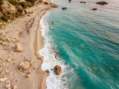 Aerial view from drone of amazing nature background. Azure wild sandy beach with rocks and clear water of Mediterranean sea at sunny day.