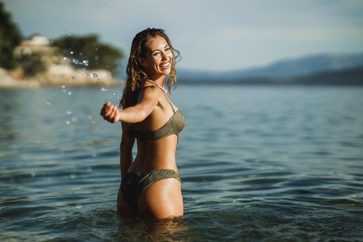 Cheerful young woman having fun in the sea water and enjoys on vacation.