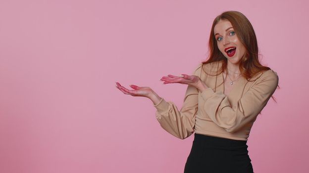 Pretty businesswoman girl showing thumbs up and pointing empty place, advertising area for commercial text, copy space for goods promotion. Young adult woman alone. Studio shot on pink wall background