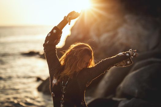 A beautiful young woman is having fun and relaxing on the beach at the sunset. 