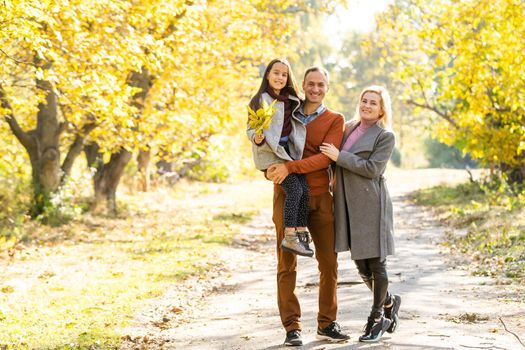 Young happy family while walking in the autumn park