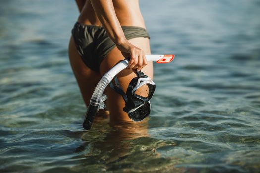 Close-up of an attractive woman with her scuba mask and snorkel walking through the sea after snorkeling.
