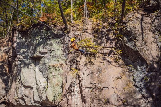 Brave little boy rappelling high among the trees in an Adventure Park for children. Extreme kid. The boy goes down the rope on a carbine.