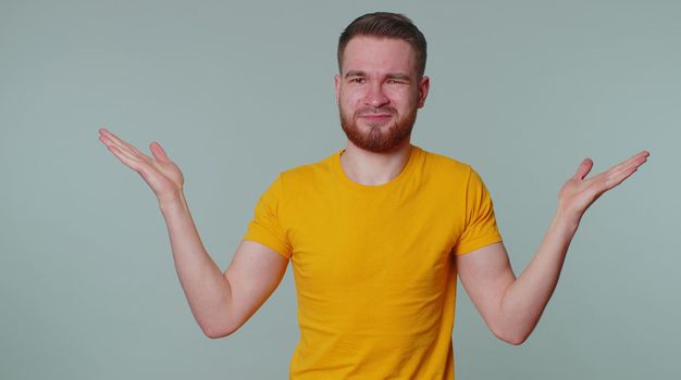 What why. Sincere tourist adult man raising hands in indignant expression asking reason of failure demonstrating disbelief irritation by troubles. Young confused guy isolated on gray wall background