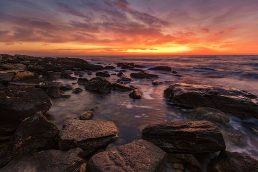 Sea sunrise at the rocky beach. Amazing view with rocky beach seascape at sunrise.