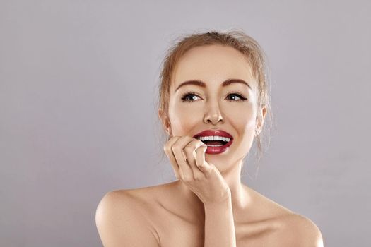 Beautiful Happy Woman Surprised on grey background. Perfect Smile. Fashion Red Lips Make-up. Expressive emotional face.