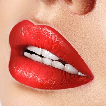 Close-up macro shot of female mouth. Sexy Glamour red lips Makeup with sensuality gesture. Magenta gloss lipstick. Full lips