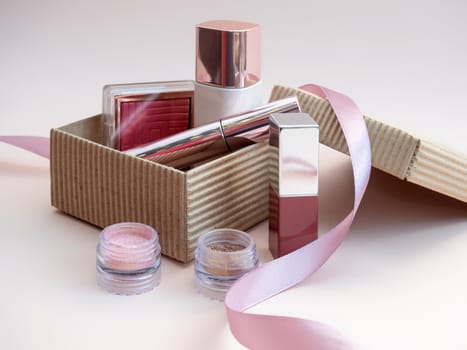 a set of cosmetics for a female face and eye makeup in a brown craft box on a pink background. photo