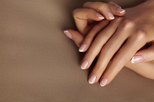 Young Female Palm on beige background. Beautiful Glamour Manicure. French Style. Nail polish. Care about Hands and Nails, clean Skin