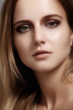 Beautiful young woman with gloss eyes and lips visage, dark blond color long hair. Beauty portrait with clean skin, glamour fashion makeup. Cosmetics, make up, hairstyle. Haircare