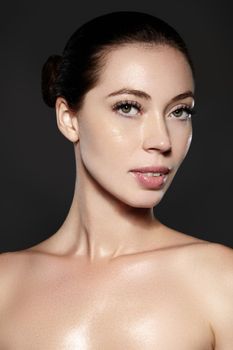 Beautiful woman show her erfect face with fashion make-up on dark grey background. Extreme eyelashes, plump lips, clean skin. Fresh spa look