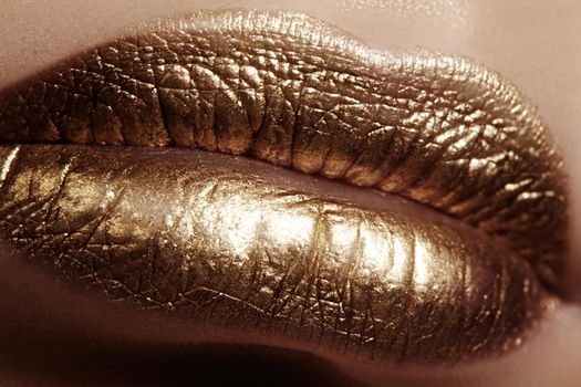 Beautiful closeup with female plump lips with gold color makeup. Fashion celebrate make-up, glitter cosmetic. Christmas style.