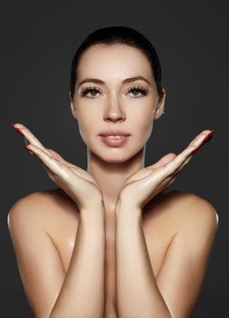 Beautiful woman show her erfect face with fashion make-up on dark grey background. Extreme eyelashes, plump lips, clean skin. Fresh spa look