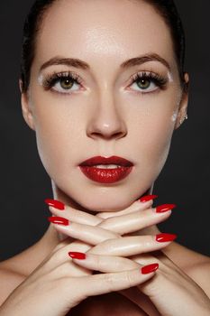 Luxury woman style vamp. Cosmetics, manicure on nails with bright red polish. Dark red lips make-up and nail color. Beauty close-up portrait of female model with red lipstick and clean skin