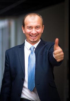 Happy business man in urban city holding thumbs up