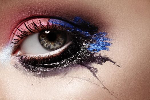 Closeup Female eyes with Bright dramatic Make-up. Great Halloween Look. Expression Makeup with Black, Pink and Dark Blue