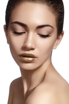 Closeup portrait with of beautiful woman face. Gold color of fashion lip makeup, clean shiny skin and glitter lipgloss. Makeup and cosmetic. Beauty style