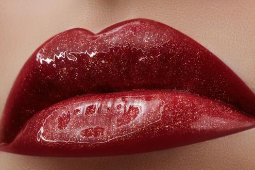 Close-up of female lips with bright makeup. Macro of woman's face. Fashion lip make-up with red gloss.Red lipgloss makeup on full female lips
